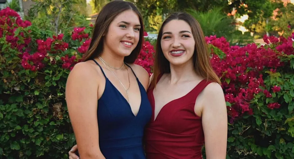Due studentesse davanti a un rigoglioso giardino con fiori rossi nel campus dell'Anaheim Union High School District.