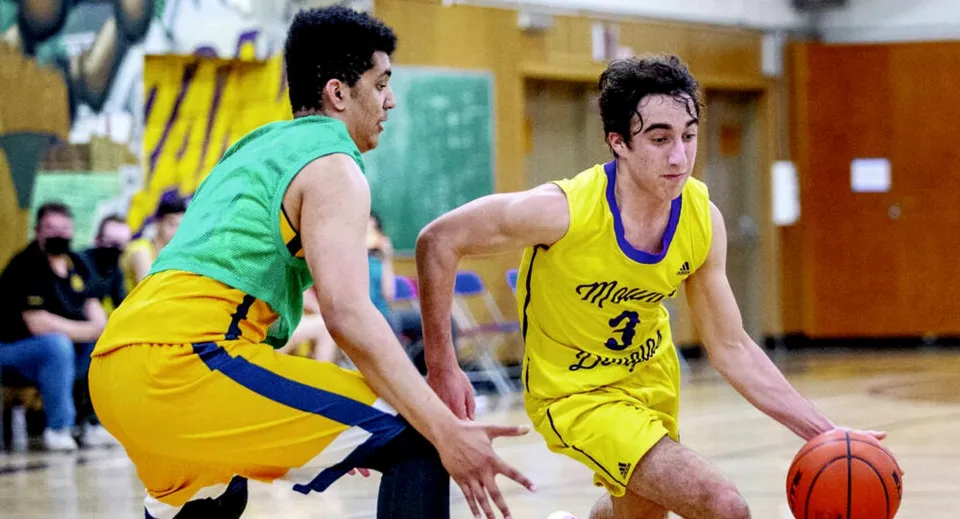 Due studenti giocano a basket sul campo sportivo della Enver Creek Secondary School.