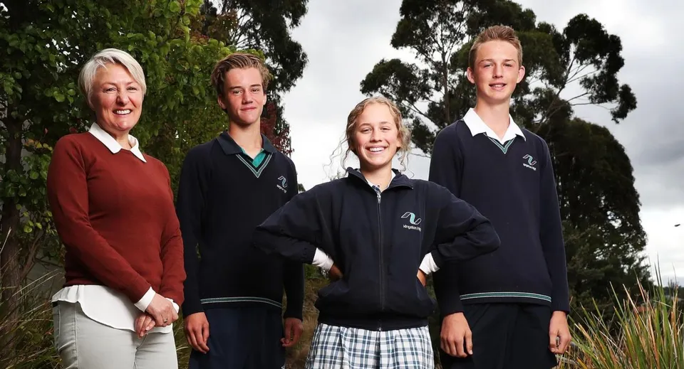 Quattro persone si trovano all'aperto davanti agli alberi nel campus della Kingston High School.