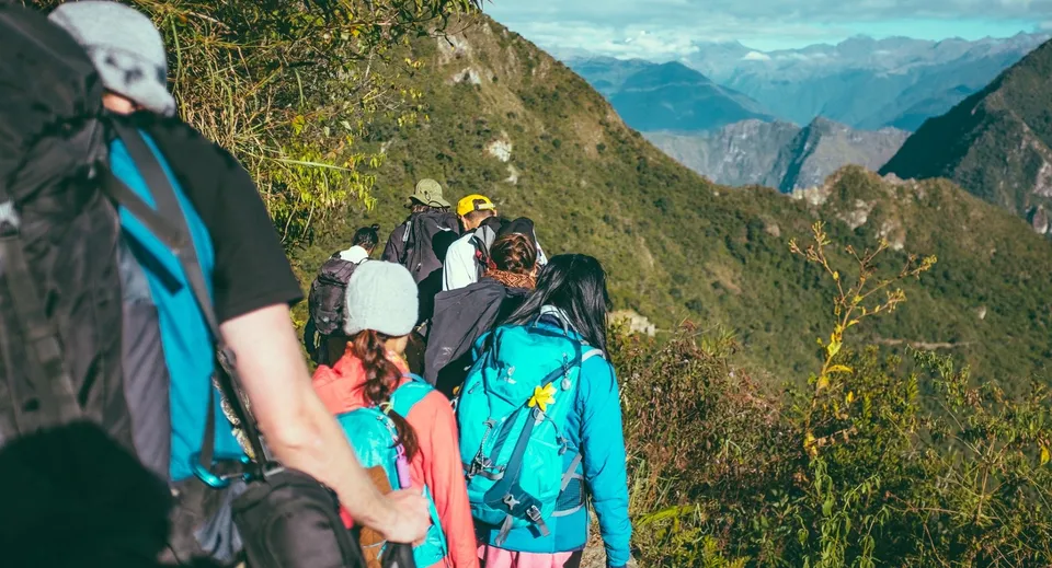 Un gruppo di studenti del Ballybay Community College fa un'escursione su uno stretto sentiero di montagna con un suggestivo paesaggio montano sullo sfondo.