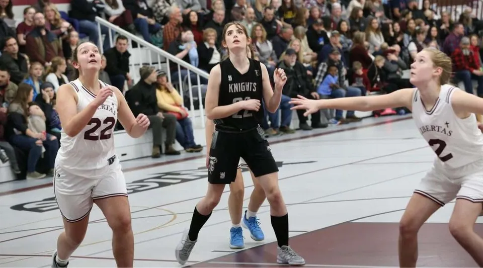 Tre studenti giocano a basket durante una partita sul campo sportivo della Algoma Christian High School.