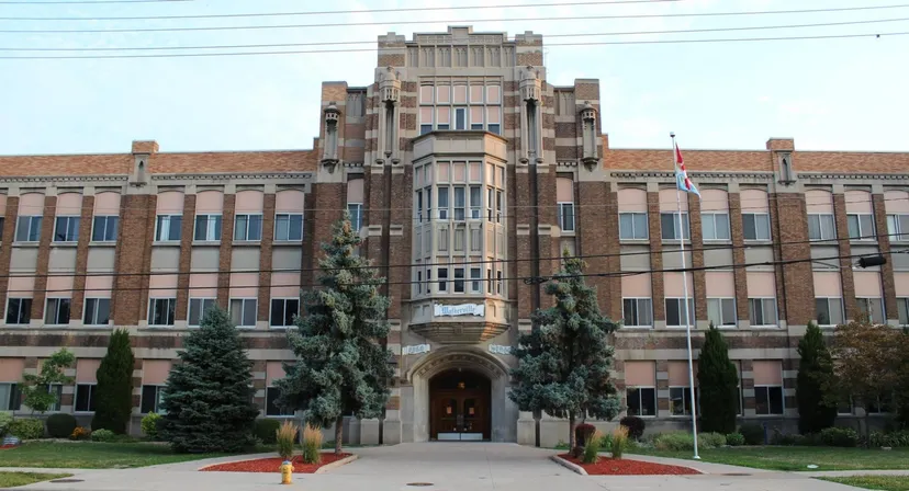 L'edificio principale storico del Walkerville Collegiate Institute circondato da alberi e da un prato ben curato.