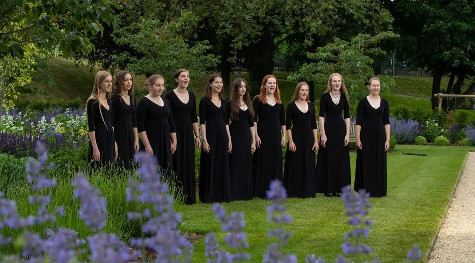 Un gruppo di giovani donne in toga nera si trova nel giardino fiorito della St. Mary’s Calne.