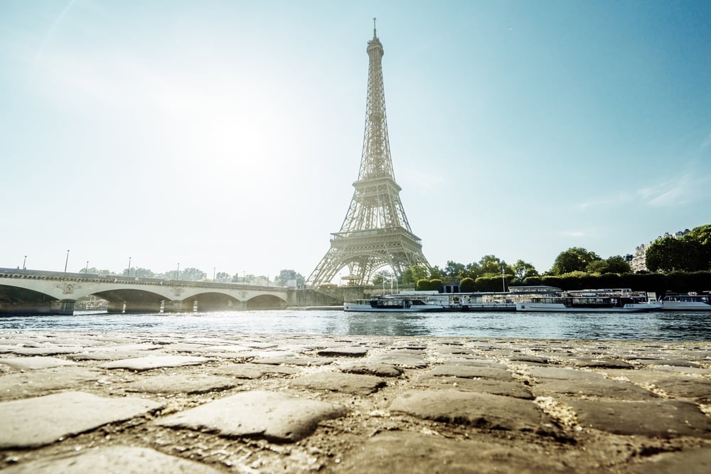 Eiffelturm an der Seine mit Brücke und Ausflugsbooten bei Sonnenschein