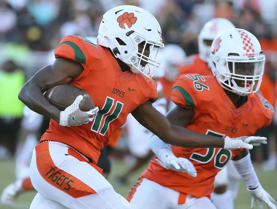 Un giocatore di football americano della Jones High School corre con il pallone.