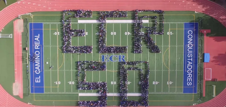 Luftaufnahme eines Footballfelds, auf dem Schüler die Buchstaben ECR 50 bilden