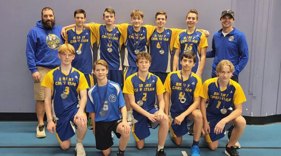 Un gruppo di studenti della Brant Christian School posa insieme con le proprie maglie da basket davanti a uno sfondo a tinta unita.