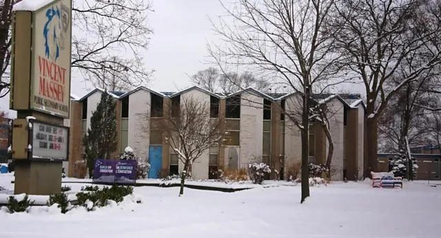 Schneebedeckte Landschaft mit mehrstöckigen Gebäuden und Schülern auf dem Campus der Vincent Massey Secondary School im Winter.