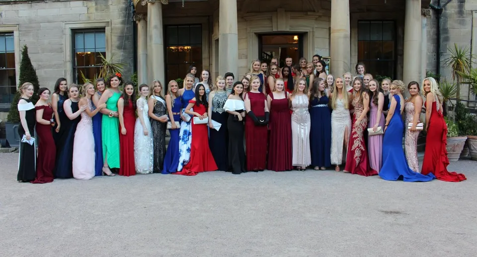 Un gruppo di donne in abito da sera si trova davanti a un magnifico edificio nel campus della Durham School.