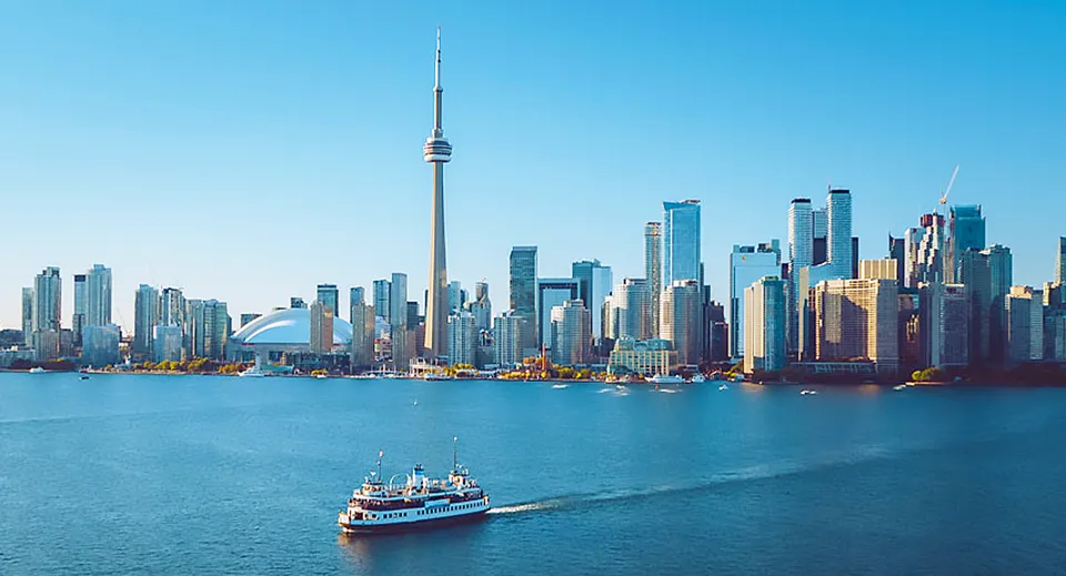 Vista sulla città con grattacieli e un traghetto in primo piano vicino al Victoria Park Collegiate Institute.