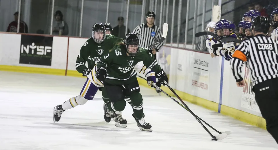 Una studentessa guida il disco durante una partita di hockey su ghiaccio, accompagnata da compagni di squadra e da un arbitro nel campus dell'Elizabeth College.