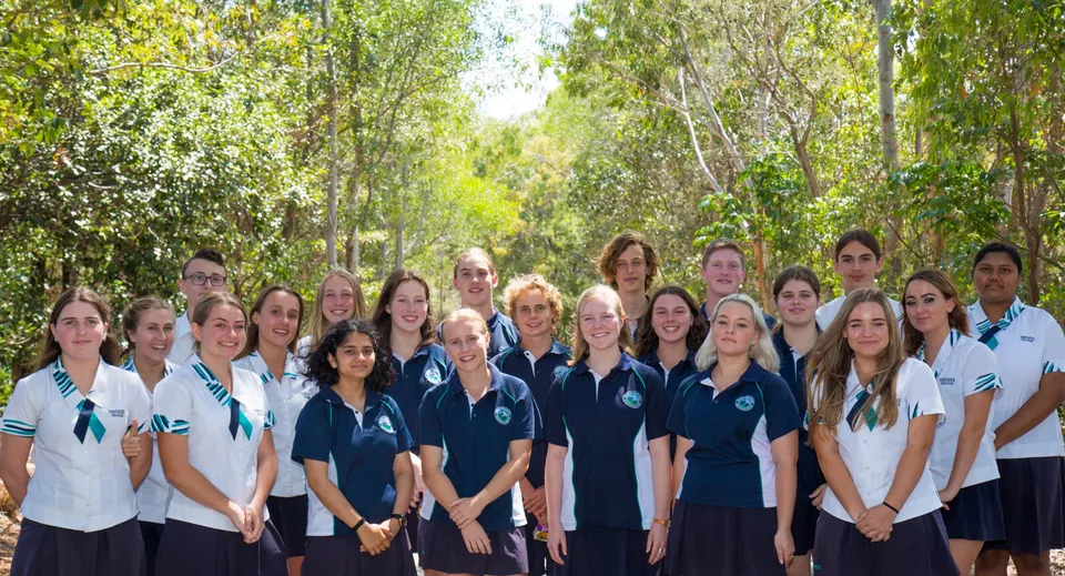 Gli studenti della Sunshine Beach State High School posano in divisa scolastica davanti agli alberi.