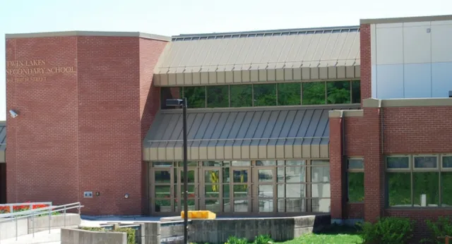 L'edificio in mattoni della Twin Lakes Secondary School con vetrate e una pensilina in metallo, circondato da aree verdi e un piazzale pavimentato.