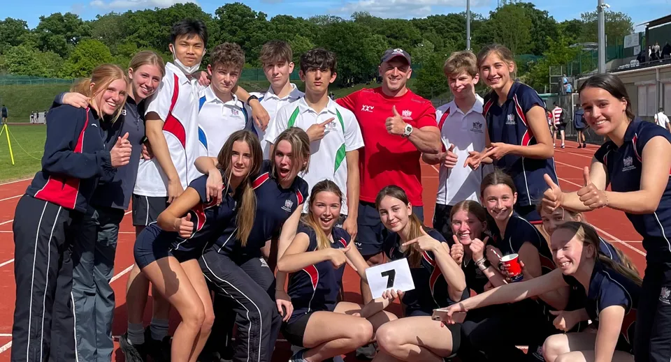 Un gruppo di giovani atleti in posa sul campo sportivo della City of London Freemen’s School sotto un cielo blu.