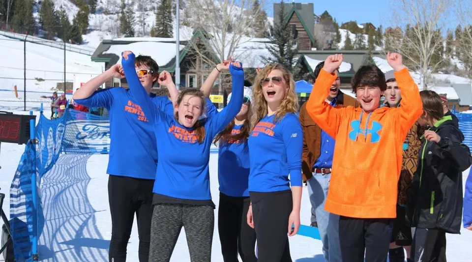 Un gruppo di studenti della Steamboat Mountain School sta nella neve davanti a un comprensorio sciistico.
