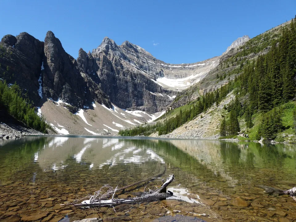 Un lago alpino con montagne innevate e pendii boscosi nel territorio della Walnut Grove Secondary School.