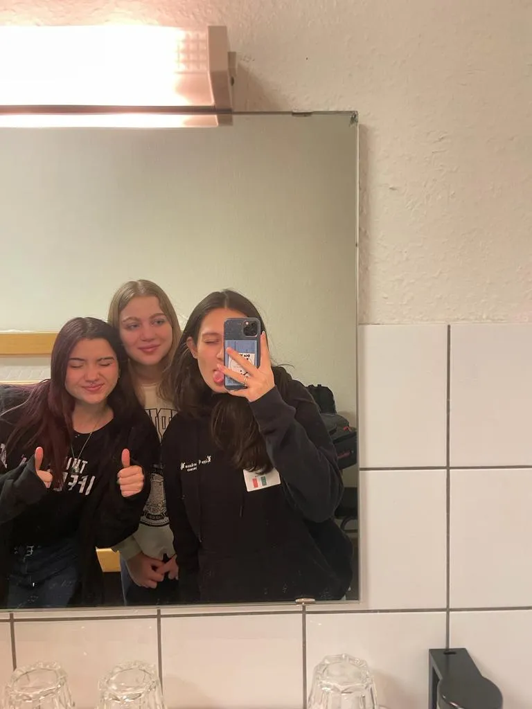 Tre ragazze si scattano un selfie allo specchio facendo il pollice in su