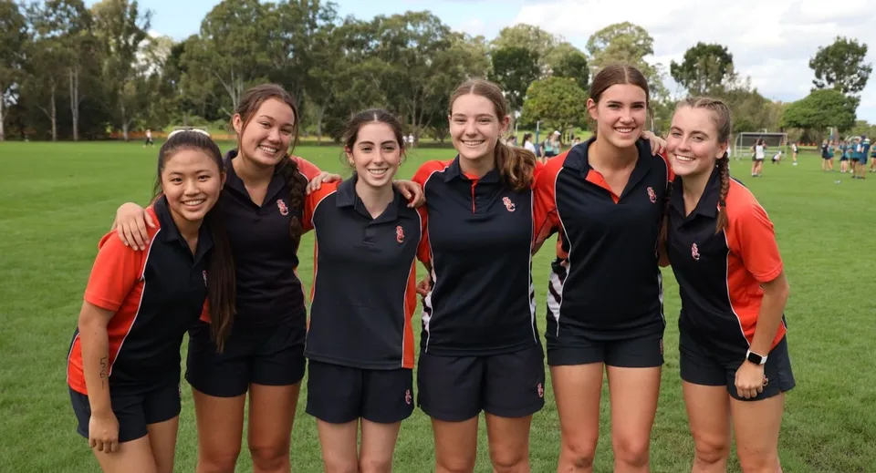 Un gruppo di giovani studentesse in tenuta sportiva si trova su un campo d'erba nel campus del Saint Stephen’s College.