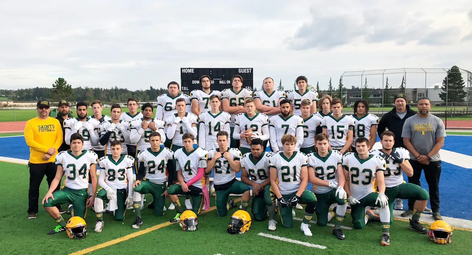 Studenti e studentesse della Langley Secondary School posano insieme sul campo sportivo davanti al tabellone segnapunti.