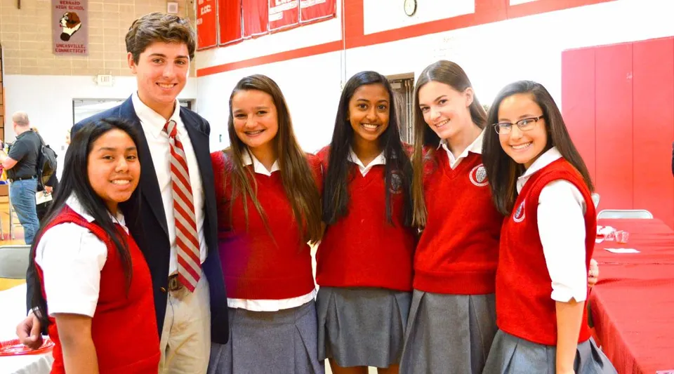 Un gruppo di studenti e studentesse in divisa rossa si trova all'interno dell'edificio scolastico della Saint Bernard School.
