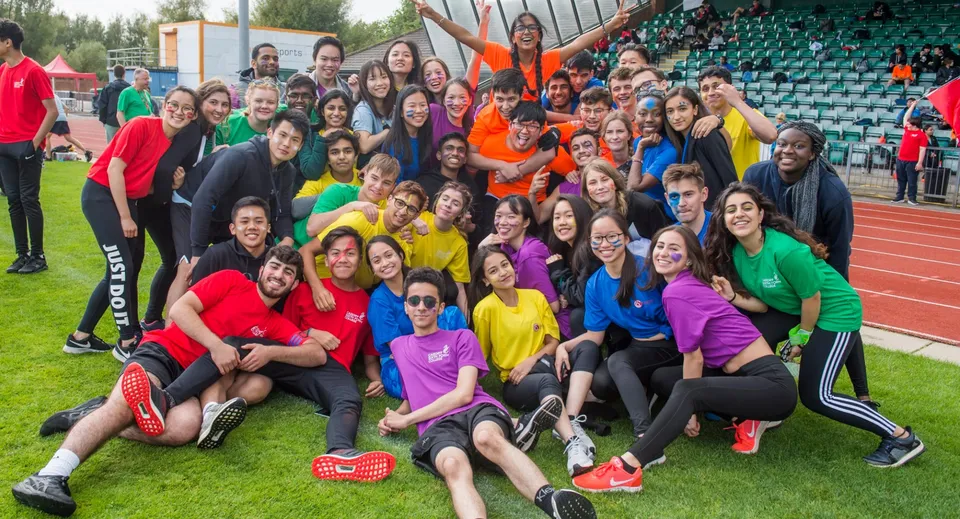 Un gruppo di studentesse indossa abbigliamento sportivo colorato e posa per una foto di gruppo sul campo da gioco del Cardiff Sixth Form College.