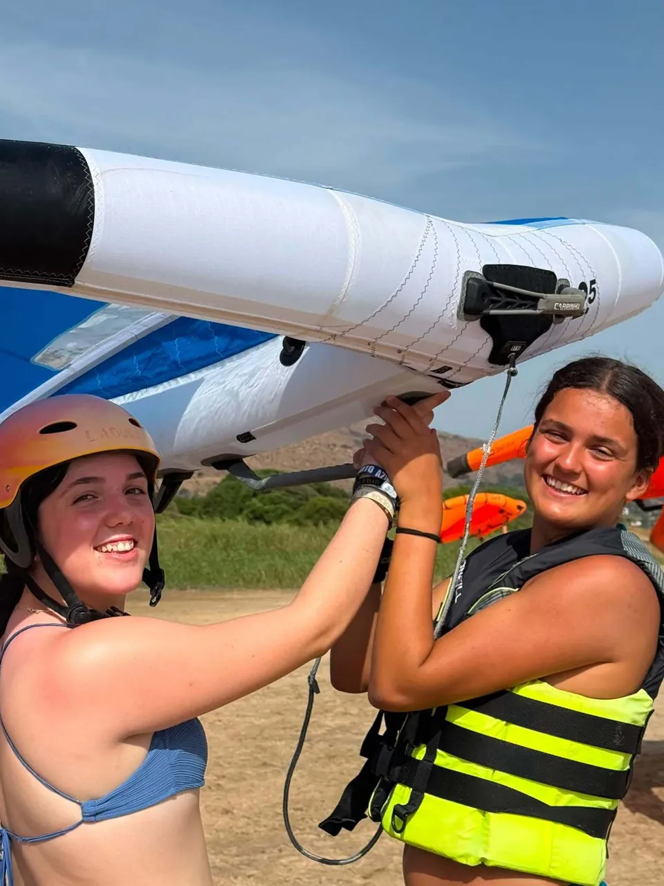 Due studentesse del Novaschool Añoreta College tengono insieme un'ala da wingfoil.