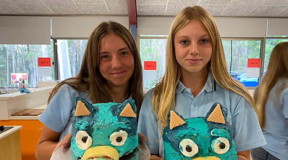 Due studentesse della Woolgoolga High School indossano magliette abbinate con un design con mostri e si trovano in un'aula.