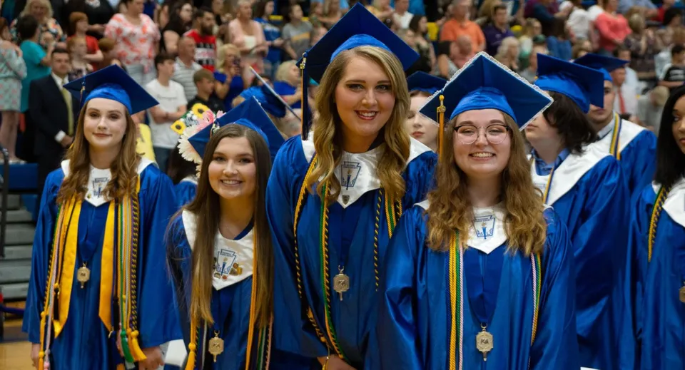 I diplomati della Bethlehem High School sono insieme in un'aula magna gremita con le toghe di laurea blu e dorate.