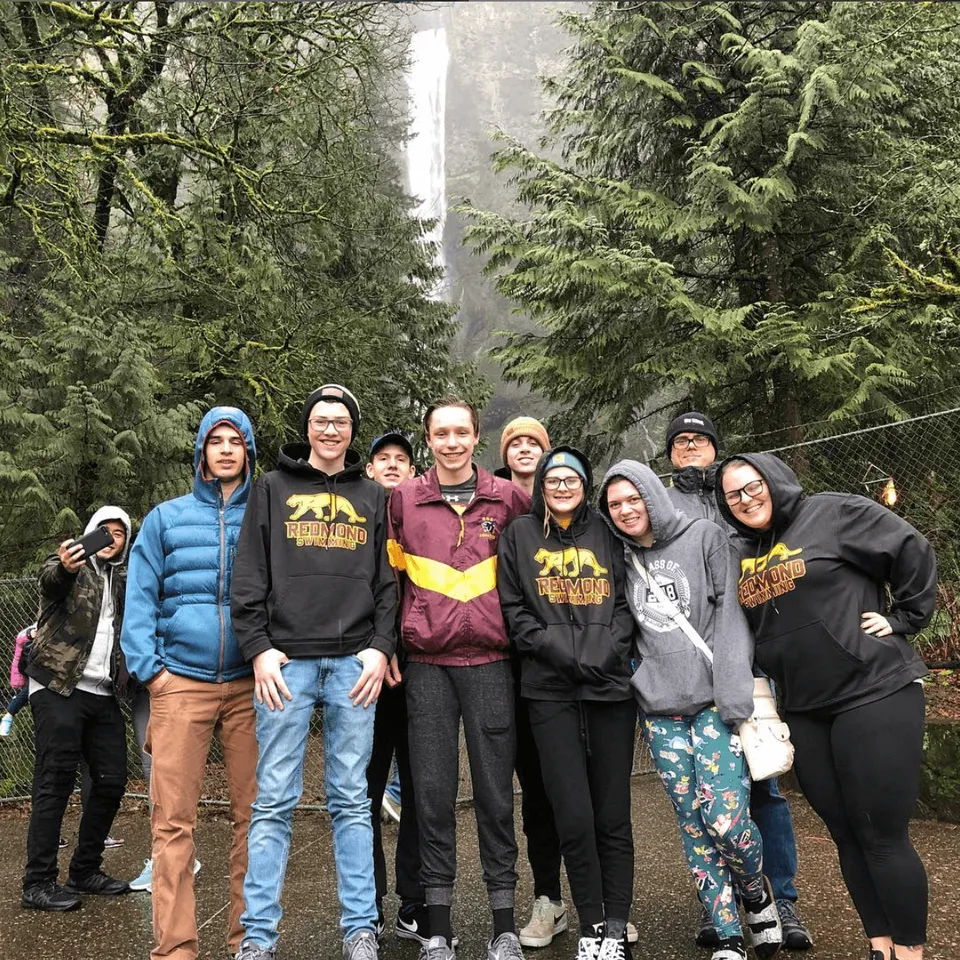 Un gruppo di studenti e studentesse si trova nel bosco nel campus della Redmond High School.