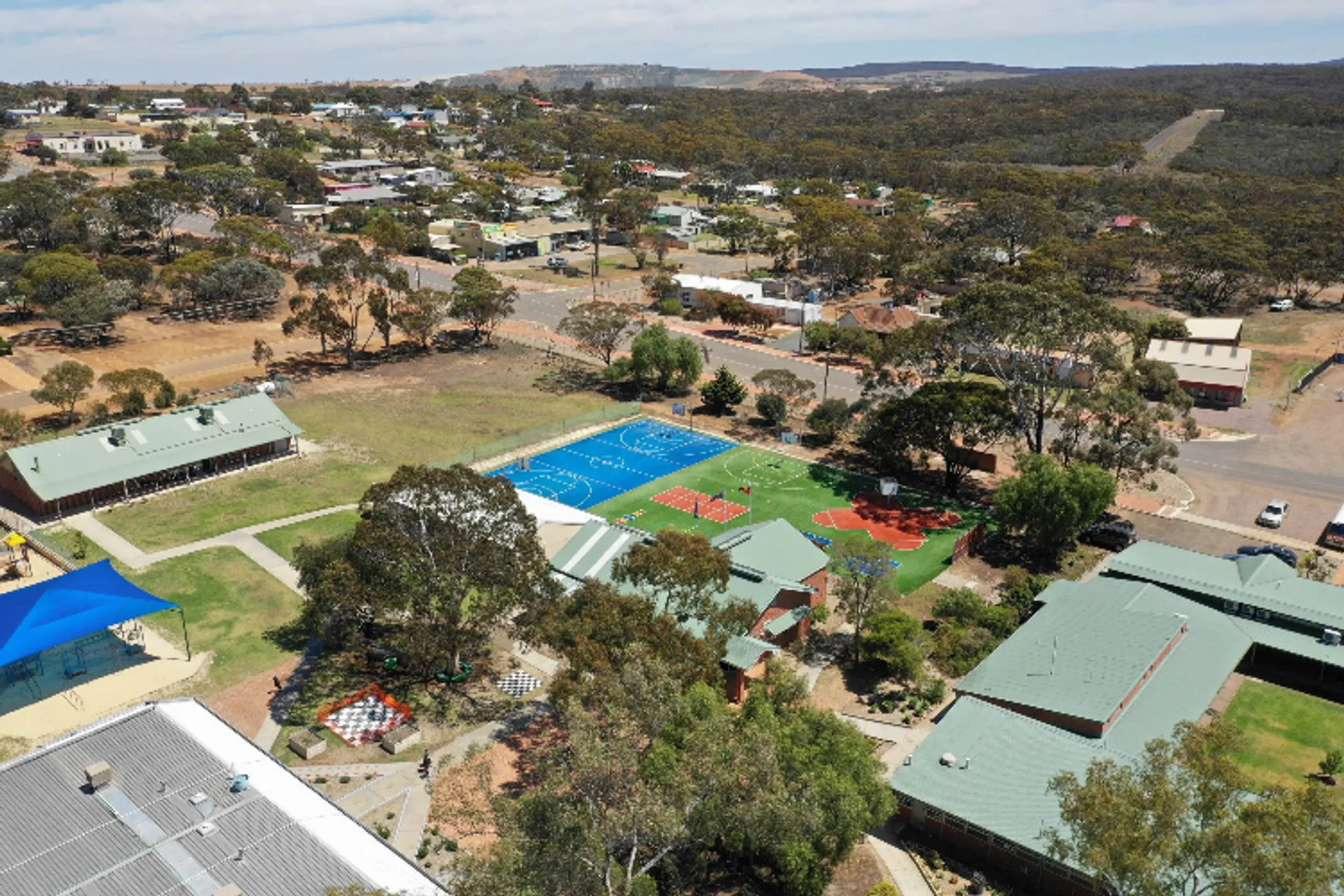 Il campo sportivo e la piscina si trovano davanti ad abitazioni ed edifici commerciali nel paesaggio collinare vicino alla Ravensthorpe District High School.