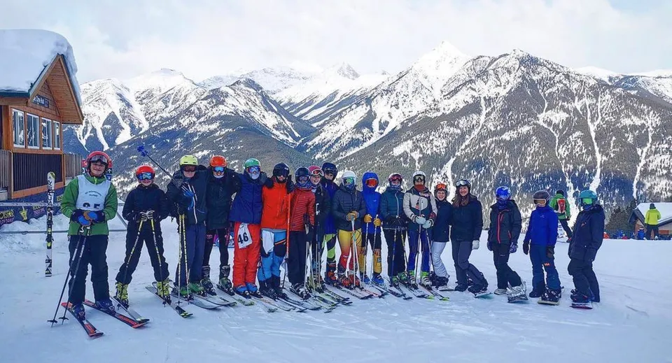 Un gruppo di studenti della Golden Secondary School in abbigliamento invernale su un pendio innevato davanti a un paesaggio montano.