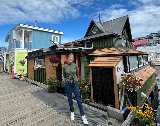 Chica posando ante casas flotantes de colores en un muelle de madera
