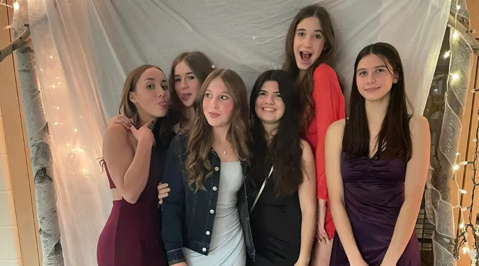 Un gruppo di studentesse del Vankleek Hill Collegiate Institute posa davanti a una tenda bianca.