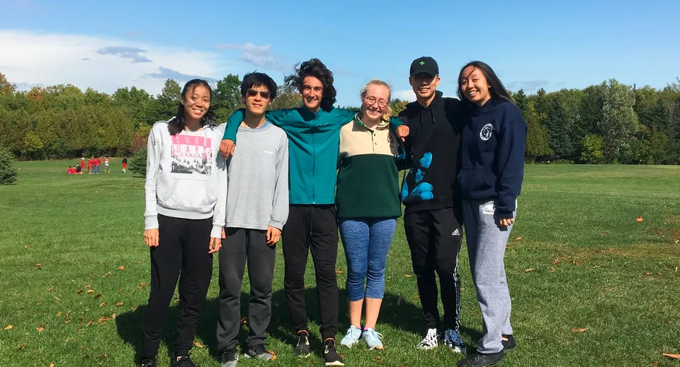 Un gruppo di studenti si trova su un prato con alberi sullo sfondo nel terreno della Thornlea Secondary School.