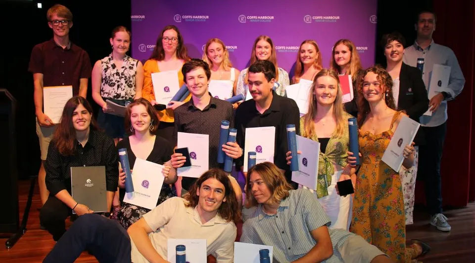 Un gruppo di studenti del Coffs Harbour Senior College posa insieme davanti a uno sfondo viola con logo.