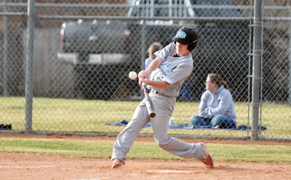 Un giocatore di baseball della Eagle Butte High School si trova sul monte del lanciatore davanti a una recinzione con spettatori sullo sfondo.