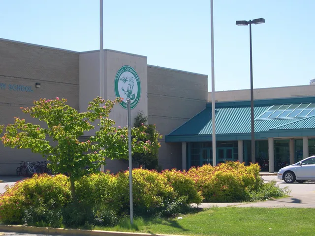 Il grande edificio con il logo verde nel campus della Sardis Secondary School è circondato da un verde lussureggiante.
