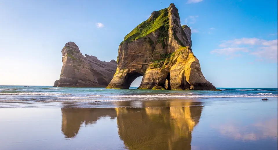 Vista su formazioni rocciose con tonalità verdi e gialle vicino a un'acqua calma nei terreni del St. Andrew's College.