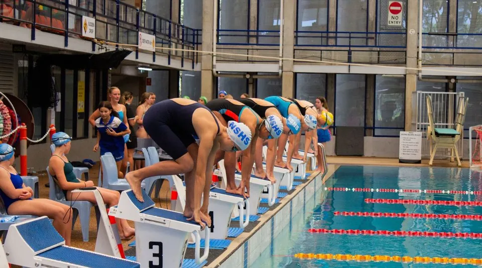 Studenti della Narrabeen Sports High School a bordo vasca in una piscina coperta durante la lezione di nuoto.