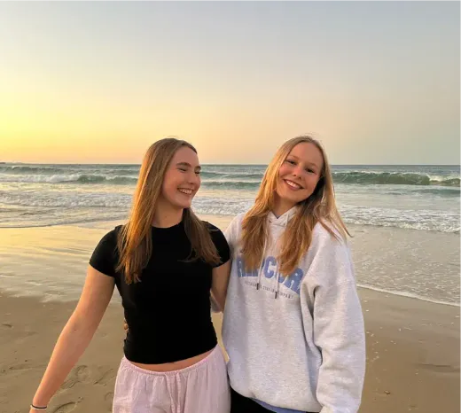 Zwei lächelnde Mädchen bei Sonnenuntergang an einem Strand in Australien