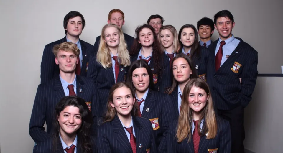 Un gruppo di studenti del Kapiti College posa insieme in uniforme scolastica davanti a uno sfondo a tinta unita.