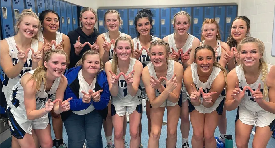 Un gruppo di giovani studentesse della squadra sportiva della Thunder Ridge High School posa in uno spogliatoio davanti agli armadietti.