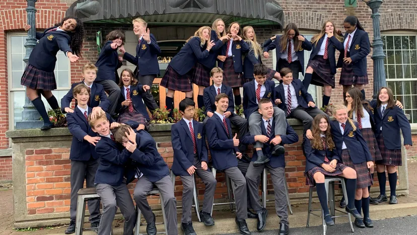 Un gruppo di studenti del Leahurst College in uniforme scolastica posa davanti a un edificio in mattoni.