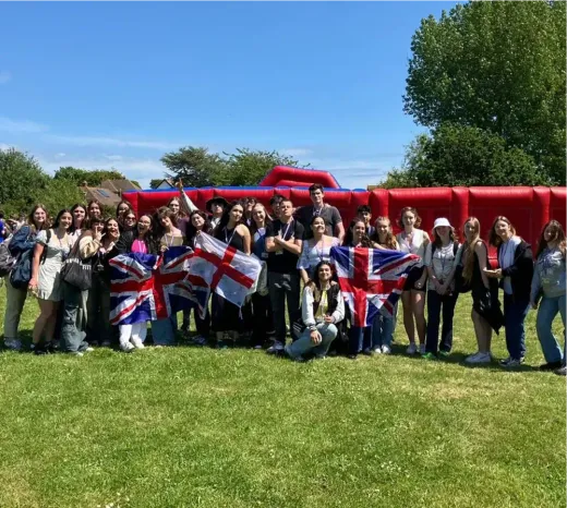Schülergruppe posiert mit englischen und britischen Flaggen auf einer Wiese in England