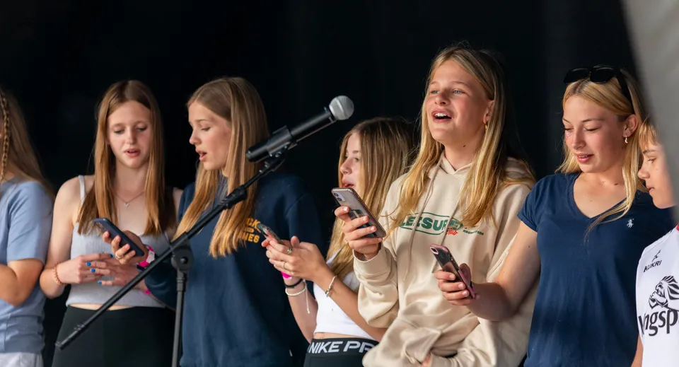 Un gruppo di studentesse del St. Joseph's College porta in scena uno spettacolo sul palco con i microfoni.
