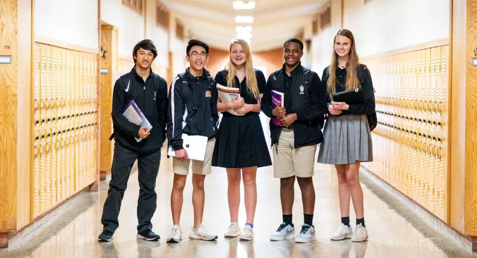 Un gruppo di studenti si trova nel corridoio con gli armadietti nel campus della St. Pius X High School.