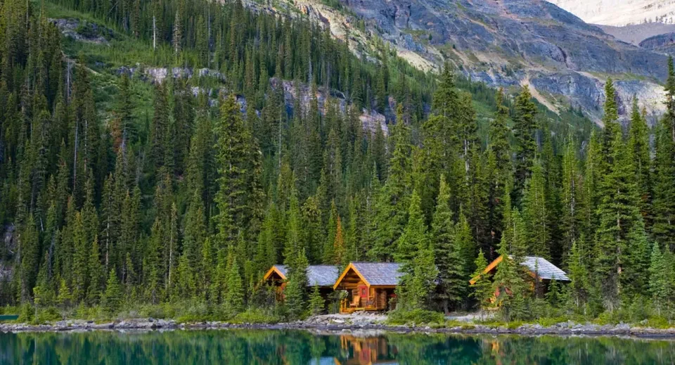 Un tranquillo paesaggio montano con lago e baite, circondato da boschi, senza un riferimento diretto al Lisgar Collegiate Institute.