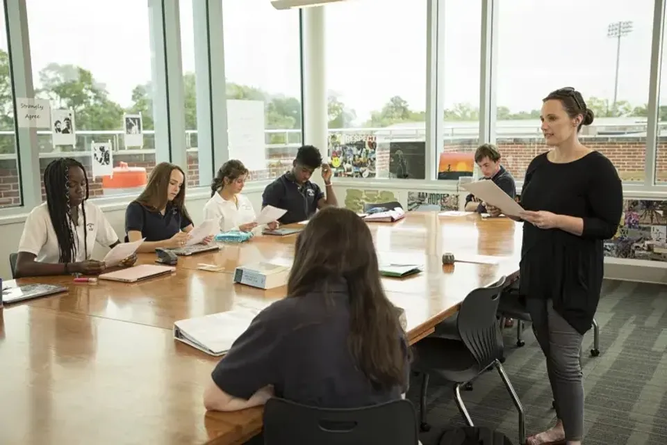Studenti della Woodward Academy lavorano insieme a un tavolo in un'aula con grandi finestre.