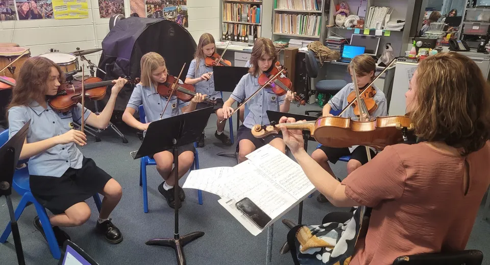 Studenti della Palm Beach Currumbin State High School suonano insieme strumenti musicali e leggono spartiti in un'aula.