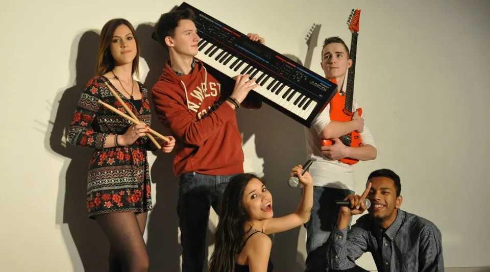 Un gruppo di studenti e studentesse con strumenti musicali nel campus dell'Itchen Sixth Form College.